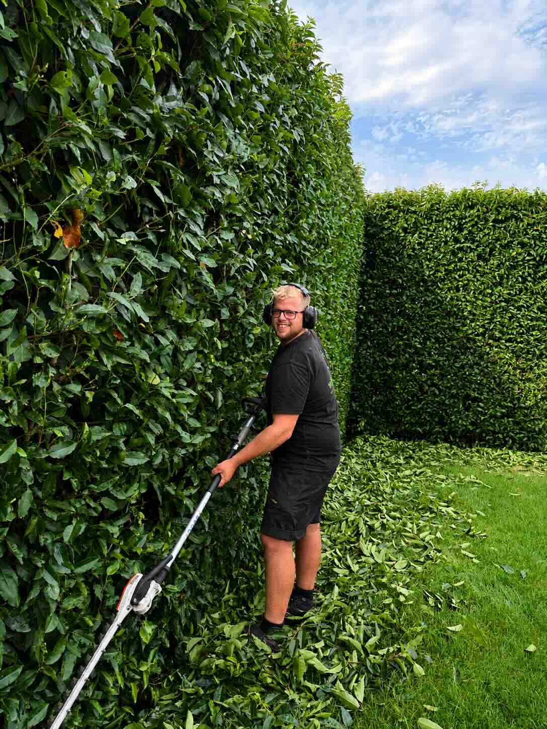 Jorg van Oijen, tuinman, aan het werk bij een hoge haag